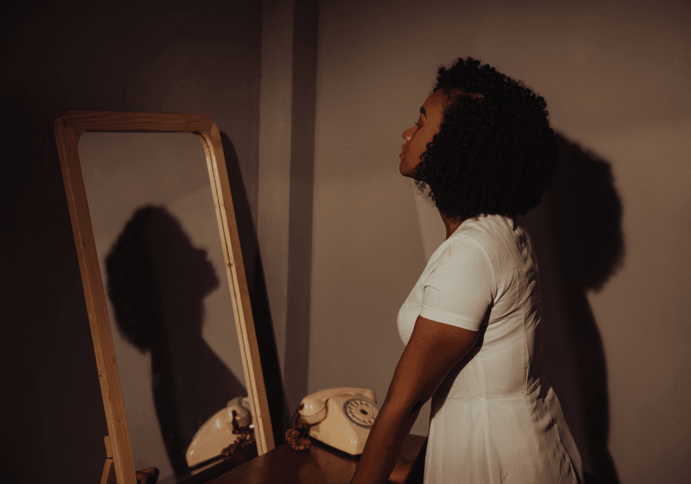 Person looking in mirror with soft lighting representing self-reflection and personal growth