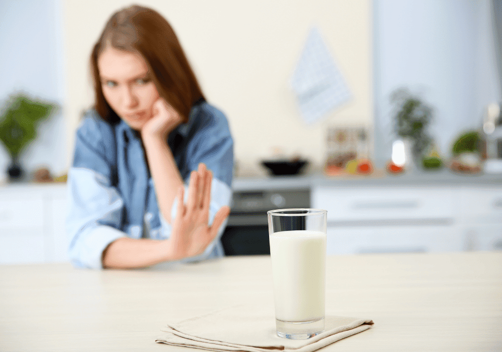 A blurred kitchen background with a cup of milk on the table and an anxious person illustrating the aspect of eating disorder identity and need for control.